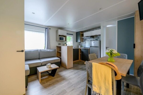 A compact living space with a kitchenette, a sofa, a dining table, and a small coffee table.