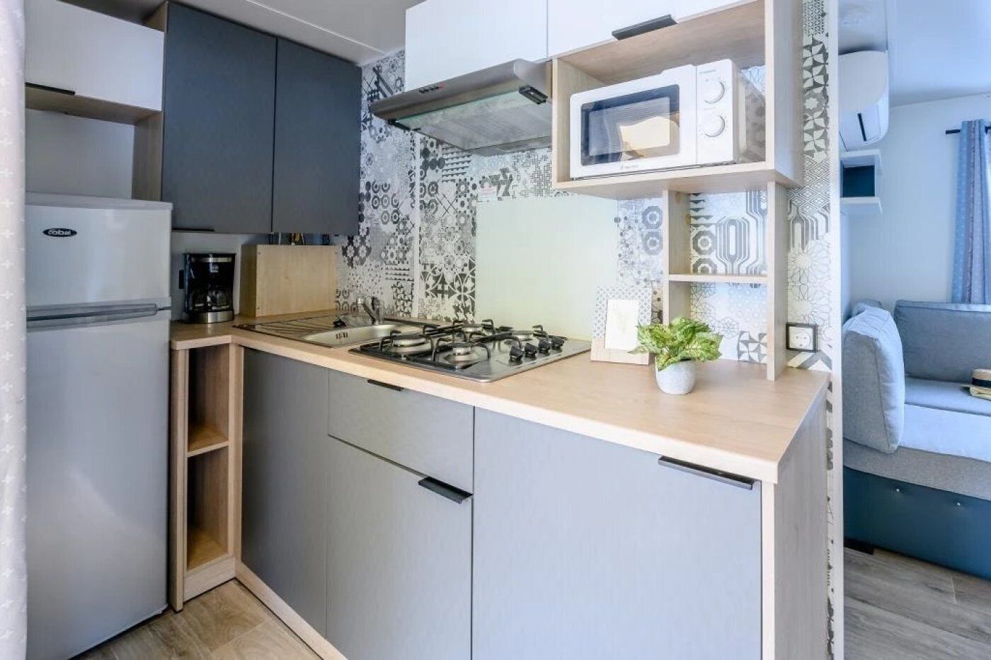 Cocina compacta con estufa a gas, microondas y cafetera.