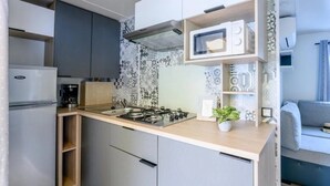 Cocina compacta con estufa a gas, microondas y cafetera.