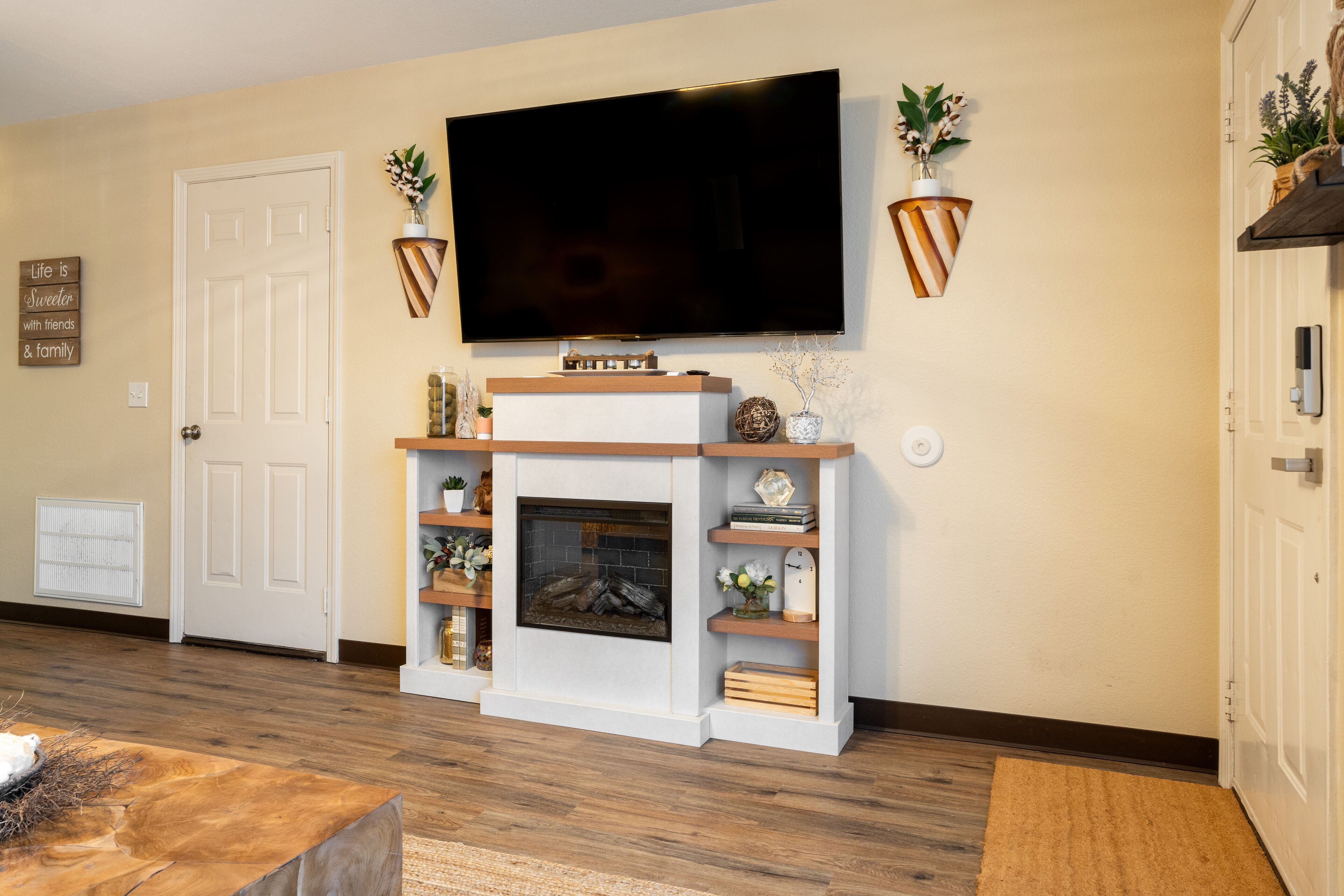 A living room with a fireplace, a mounted TV, and decorative shelves. - Townhome with a peaceful, soothing vibe, featuring KING and QUEEN size beds (Springdale)