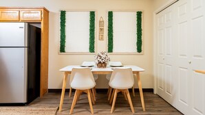 A kitchen with a refrigerator, wooden cabinets, a dining table with two chairs, and a window with green foliage. - Townhome with a peaceful, soothing vibe, featuring KING and QUEEN size beds (Springdale)
