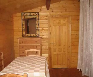 Cozy cabin with a bed, dresser, and mirror, set amidst a sloped ceiling.