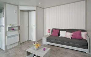 A modern living room with a grey sofa, a white coffee table with a vase, and a white wardrobe.