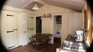 Ett kompakt kök med ett matbord och stolar, en gasspis och träväggar.