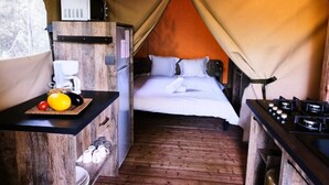 A tented accommodation with a bed, a small kitchenette, and a table with breakfast items. - ZEcamping 4 étoiles piscine chiens acceptés tente clim 34m2 5 pers (Orgon)