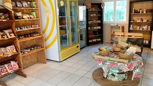 A room with wooden shelves stocked with snacks, a yellow and white refrigerator, and a tropical-themed table with baskets. - ZEcamping 4 étoiles piscine chiens acceptés tente clim 34m2 5 pers (Orgon)