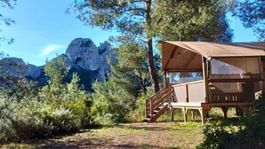A wooden cabin with a covered porch, surrounded by trees and mountains. - ZEcamping 4 étoiles piscine chiens acceptés tente clim 34m2 5 pers (Orgon)