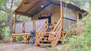 A wooden cabin with a covered porch, a bicycle, and a small table. - ZEcamping 4 étoiles piscine chiens acceptés tente clim 34m2 5 pers (Orgon)