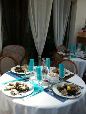 Enjoy a communal dining experience with round tables set for a meal, surrounded by comfortable chairs and a view of the outdoors.
