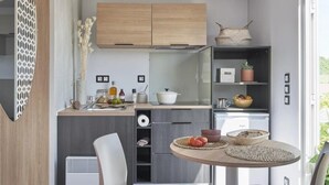 A modern kitchen with wooden cabinets, a built-in stove, and a dining area with a round table and two chairs.