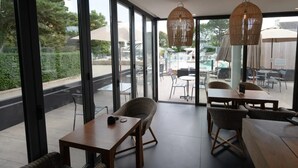 A modern indoor space with large windows, wicker furniture, and hanging light fixtures.