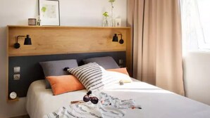 A neatly made bed with a striped blanket, a wooden headboard, and two bedside lamps. - ZEcamping 4 étoiles 200m plage piscine couverte locatif TV LV BBQ 32m2 (Névez)