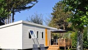 Une petite cabane à un seul étage, dotée d’une porte coulissante, d’une terrasse avec deux chaises et d’une plateforme en bois.