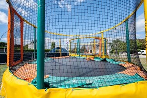 A trampoline enclosed by a safety net with a yellow and green frame.