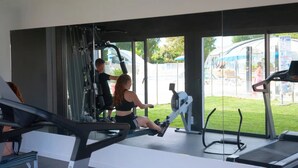 Une salle de sport équipée de machines de cardio, d’un tapis de course et d’un rameur.