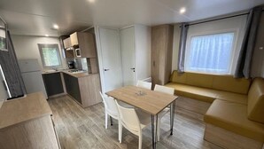 Un espace de vie compact comprenant un coin cuisine, un coin repas et un espace détente avec un canapé et une fenêtre.
