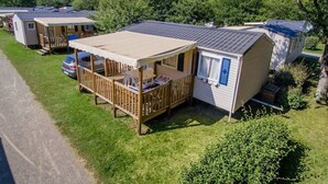 A mobile home with a covered porch and a car parked nearby. - ZEcamping 4 étoiles piscine couverte animations jacuzzi locatif TV 28m2 (Aureilhan)