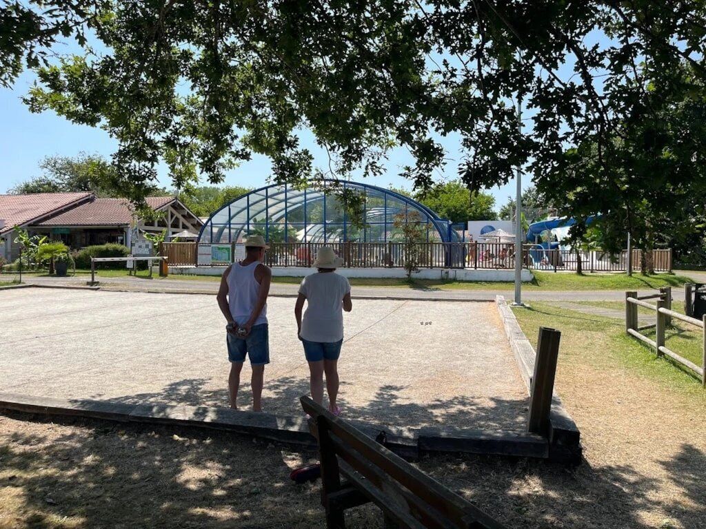 Een park met een speeltuin, een overdekte constructie en een houten bank.