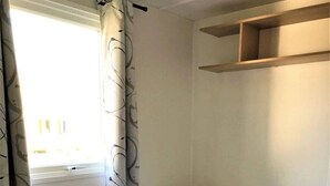 A dormitory room with two single beds, a window with curtains, and a built-in shelf above the beds. - ZEcamping 4 étoiles animé piscine couverte dog friendly jacuzzi locatif TV (Aureilhan)