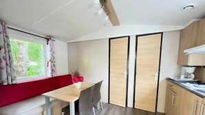 Cocina compacta con comedor, un banco y ventana con cortinas.