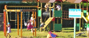 Um parquinho com diversas estruturas de lazer, incluindo balanços, um escorrega e áreas para escalar.