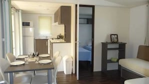 Un espace de vie compact comprenant un coin repas, une kitchenette et une chambre.