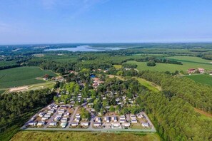 An aerial view of a campground with multiple RVs and trailers, surrounded by dense forests and a lake in the background. - ZEcamping 4 étoiles familial piscine couverte pet friendly hammam tente TV (Azur)