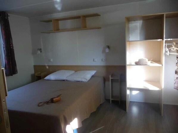 Ein Schlafzimmer mit einem Bett, Nachttischen, einem Kleiderschrank und einem Spiegel.