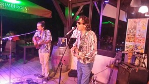 A stage with two musicians performing, a microphone stand, and a bar area with various items. - ZEcamping 4 étoiles familial piscine couverte pet friendly hammam tente TV (Azur)