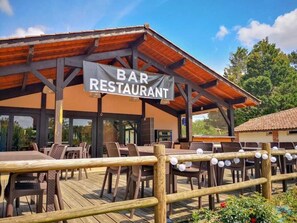 A bar restaurant with outdoor seating and a wooden deck. - ZEcamping 4 étoiles piscine couverte pet friendly club enfant tente TV (Azur)