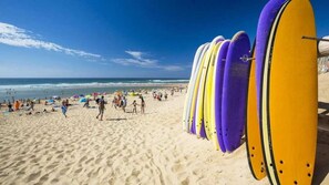 A beach with surfboards lined up and people walking on the sand. - ZEcamping 4 étoiles piscine couverte pet friendly club enfant tente TV (Azur)