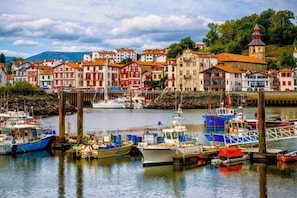 A harbor with boats docked, surrounded by colorful buildings with red and white facades.