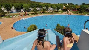 Una piscina con tobogán y gente disfrutando del agua.