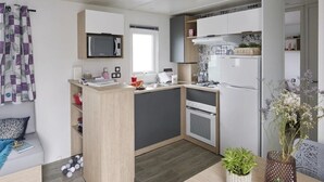 Una cucina compatta con forno a microonde, fornelli e frigorifero, pensili in legno e una finestra.