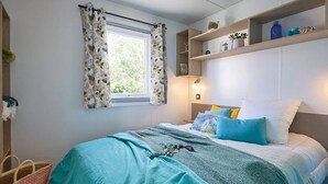Una camera da letto con un letto, una finestra con tende, un comodino e uno scaffale con oggetti decorativi.