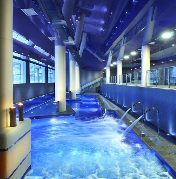Una piscina interior con agua cristalina, una escalera y un diseño arquitectónico moderno.