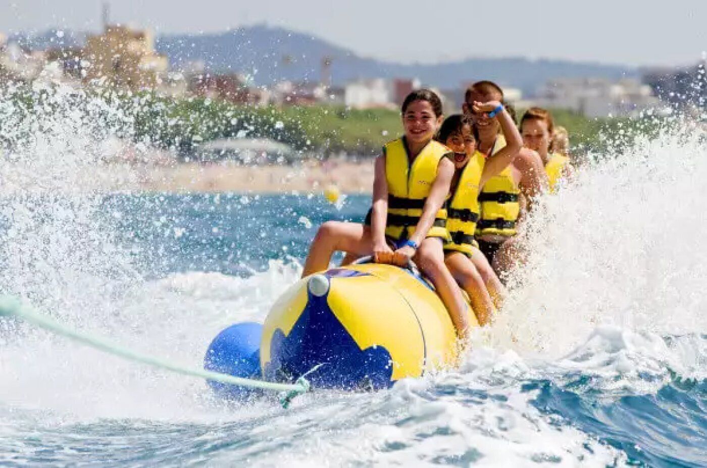 A group of people on a water ride with a yellow and blue ball, wearing life jackets.