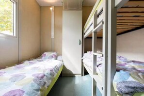 Een studentenkamer met twee stapelbedden, een raam en een deur.
