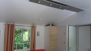 Ein modernes Zimmer mit Esstisch, einem roten Sofa, einem Fenster mit Vorhängen und einer Tür.
