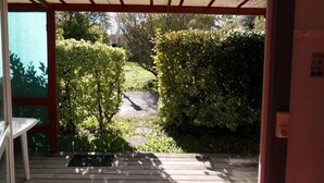 A wooden deck with a pergola, surrounded by greenery and a pathway. - ZEcamping 3 étoiles piscine pet friendly bien-être locatif TV 22m2 4 pers (Urt)