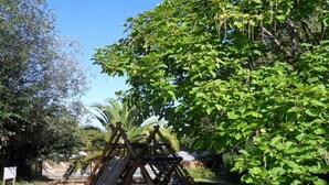 A playground with a wooden swing set and a slide, surrounded by lush greenery and trees. - ZEcamping 3 étoiles piscine pet friendly bien-être locatif TV 22m2 4 pers (Urt)