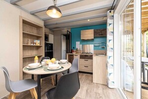 A compact kitchen with a dining area, wooden cabinets, and a large window.