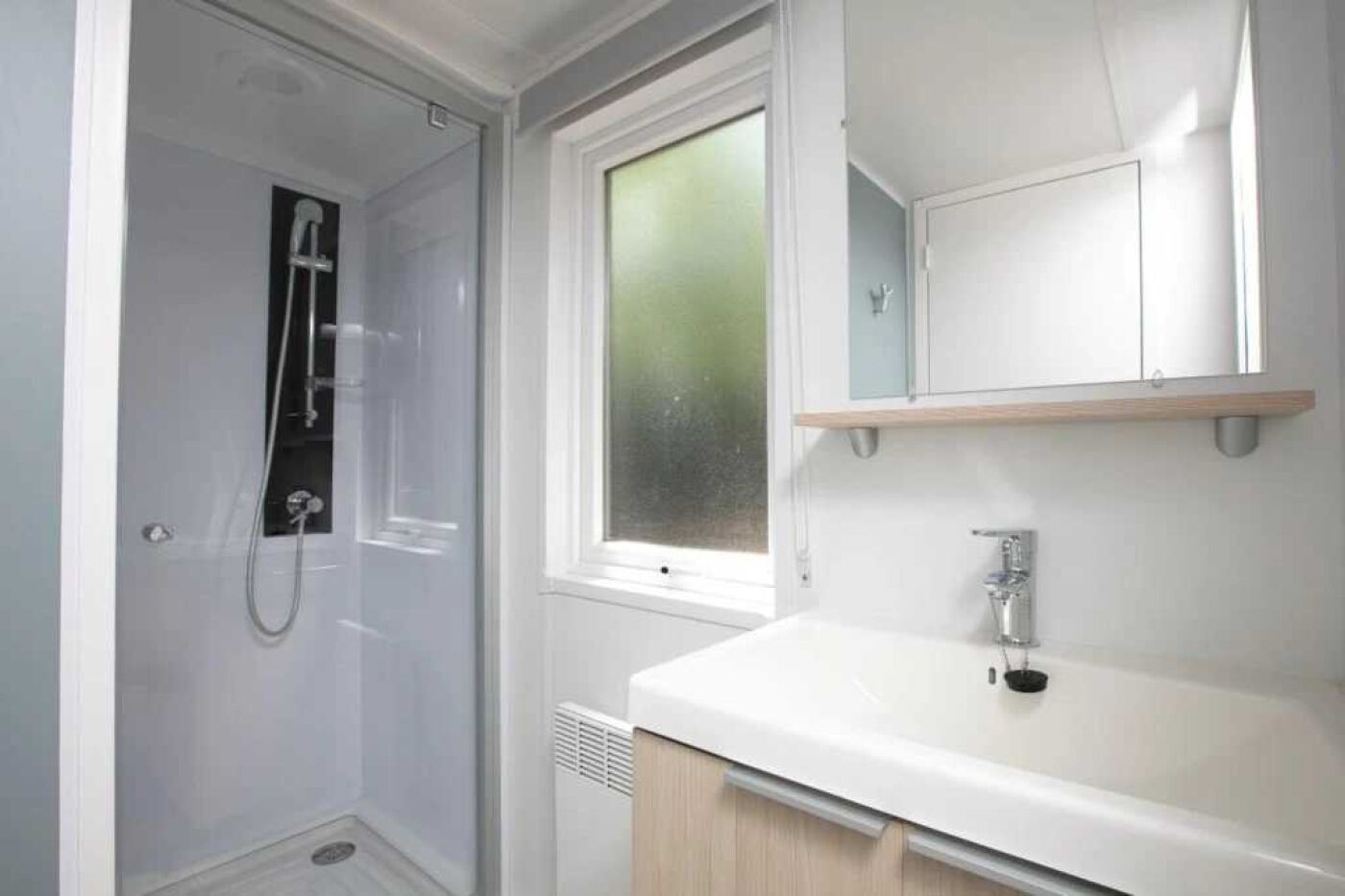 A bathroom with a shower, a sink, and a window.