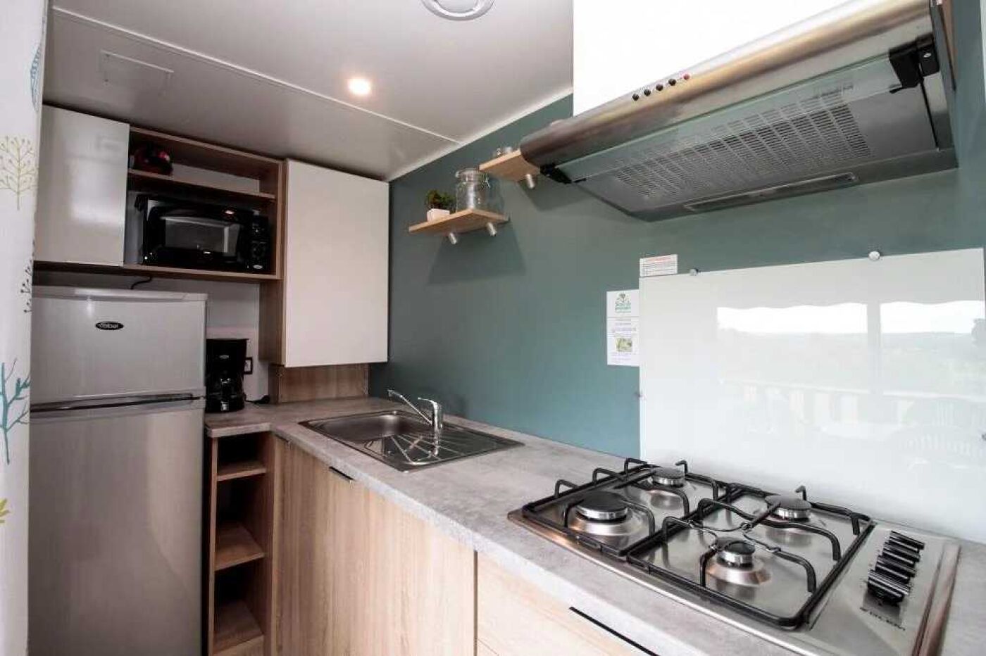 Una cucina compatta con un fornello a gas, un forno a microonde e un frigorifero.