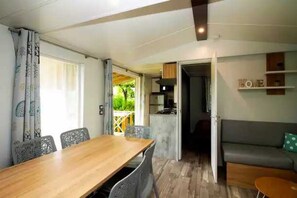 Relax in this stylish room with a dining table, sofa, and large window overlooking a serene outdoor space.