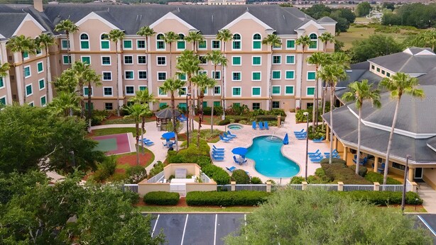 A hotel with a swimming pool, palm trees, and a view of the cityscape. - Suites at Lake Buena Vista close Disney Spring (Orlando)