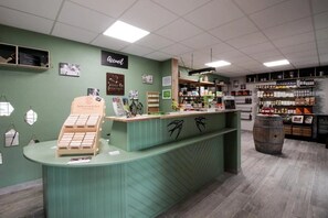 A reception desk with a green counter, a sign above it, and a wooden barrel in the background.