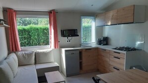 A compact kitchen with a dining area, a built-in oven, and a microwave. - ZEcamping 3 étoiles familial piscine couverte locatif TV LV BBQ 33m2 (Les Moutiers-en-Retz)