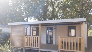 A small, single-story wooden cabin with a front porch, a door, and a small window. - ZEcamping 3 étoiles familial piscine couverte locatif TV LV BBQ 33m2 (Les Moutiers-en-Retz)
