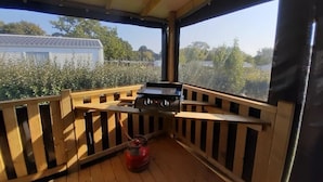 Un espacio al aire libre techado con una parrilla y un cilindro de gas.